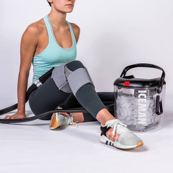 Patient resting at home with an ICEMAN Clear3 knee wrap fitted during recovery